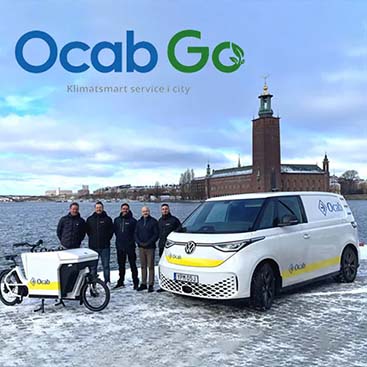 Bild på Ocab-go personal framför två tjänstefordon med Stockholms stadshus i bakgrunden, logotypen syns högst upp i bild.